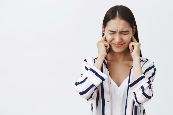 Daughter covering ears being displeased of loud fight of parents, feeling intense and timid. Portrait of unhappy and sad cute woman in blouse, frowning with closed eyes trying not hear noise gürültü günü nedir